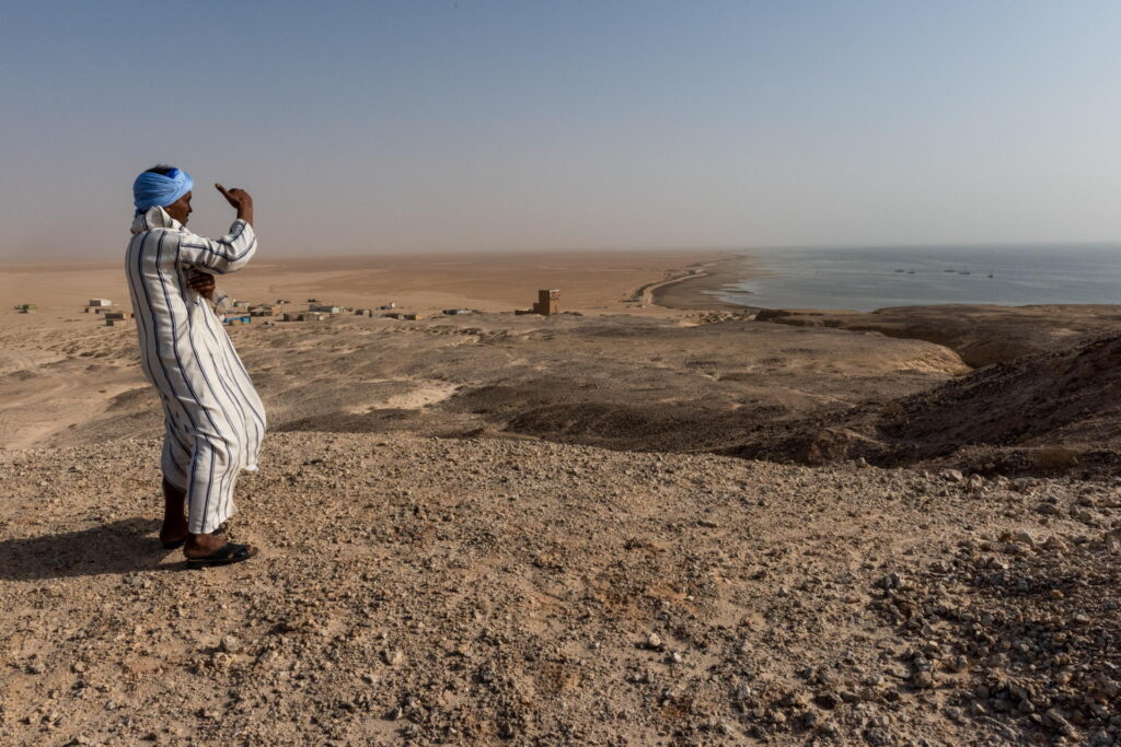 14 January 2019, Banc D'Arguin, National Park Nature Reserve, Mauritania. The small fishing village Arkei is seen in the distance. Mr. Iveko Mohammed, has always had a passion for the environment and the Banc d'Arguin where he grew up. He has now been working as the deputy head of surveillance guards for 12 years, and he knows the park as his own backyard.  

THE PROJECT: The Biodiversity and Hydrocarbon Project aimed at integrating marine and coastal biodiversity in the policies and practices of the offshore oil and gas industry so that it does not degrade marine and coastal natural resources and ecosystems. Mauritania's marine and coastal environments support significant biological diversity. The Banc d'Arguin National Park is a UNESCO World Heritage site. Banc d'Arguin is a nesting and breeding area for birds; each winter, it is home to the largest concentration of Palearctic migratory birds, and is a habitat for a large number of marine animals. 

https://open.undp.org/projects/00059643