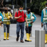 FILE PHOTO: Migrant workers in essential services wearing safety vests cross a street at Orchard Road, amid the coronavirus disease (COVID-19) outbreak in Singapore, May 27, 2020. REUTERS/Edgar Su/File Photo